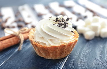 Tasty tartlet with whipped cream on wooden table