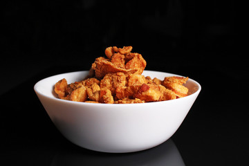 Cracklings greaves. Delicious crunchy crisp cracklings pork greaves on black reflective studio background. Isolated black shiny mirror mirrored background for every concept.