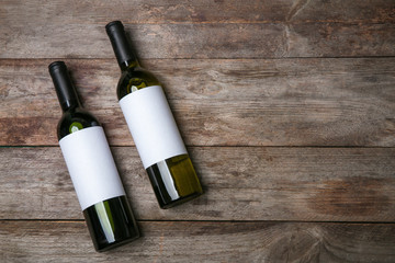 Bottles of wine with blank labels on wooden background. Mock up for design