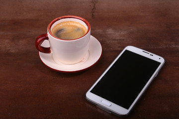 Fototapeta na wymiar Coffee cup and smartphone on wooden table. View from above