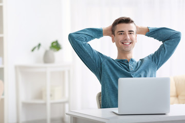 Young man using modern laptop at table