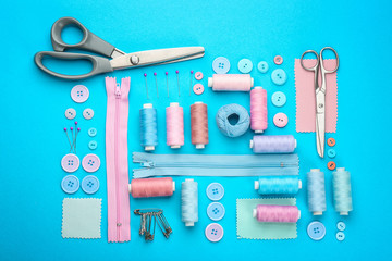 Different threads and sewing accessories on color background