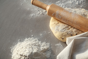 Raw dough and rolling pin on table