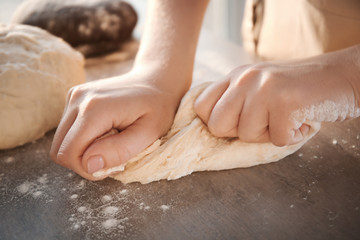Woman kneading dough on table, closeup