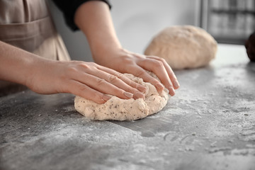 Woman kneading dough on table, closeup