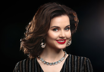 Beautiful woman with elegant jewelry on dark background