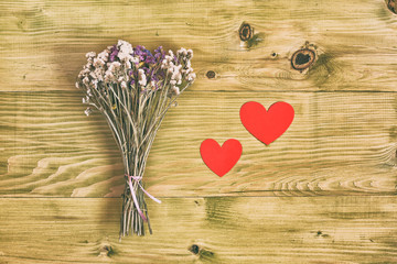 Bouquet of flowers with heart shapes on wooden table.