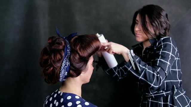 hairdrasser tie a bandana in bow and apply hairspray in pinup style 
