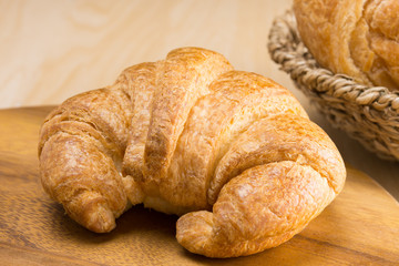 closed up fresh croissant on wooden cutting board 