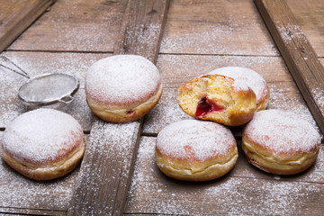 Tradycyjne pączki z cukrem pudrem i dżemen na drewnianym tle. Miejsce na tekst. 