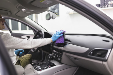 A man cleaning car interior, car detailing (or valeting) concept. Selective focus. 