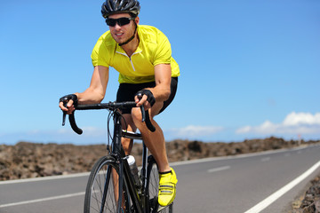 Road bike cyclist man sport athlete training cardio workout on racing bicycle. Male biker biking outdoors training for triathlon.
