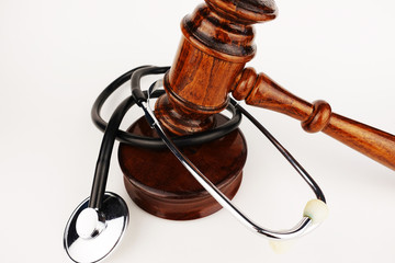 Malpractice concept with wooden judge hammer and stethoscope on white background
