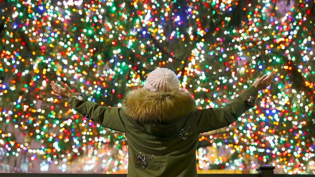 Happy girl on the background of the Rockefeller Christmas tree in New York. Beautiful Christmas Tree at Rockefeller center