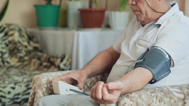 An elderly man measures blood pressure at home