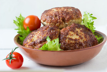 Homemade cutlets, tomatoes and lettuce on a plate.