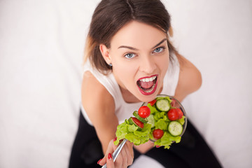 Young woman eating healthy salad after workout