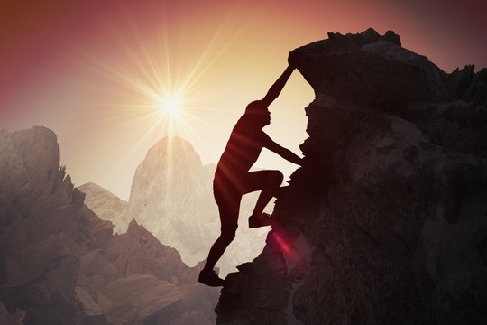 Silhouette Of Young Man Climbing On Mountain.