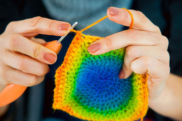 A woman knits a crocheted colored bright rug or napkin. Knitted fabric.