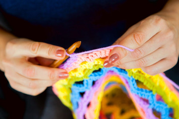 A woman knits a crocheted colored bright rug or napkin. Knitted fabric.