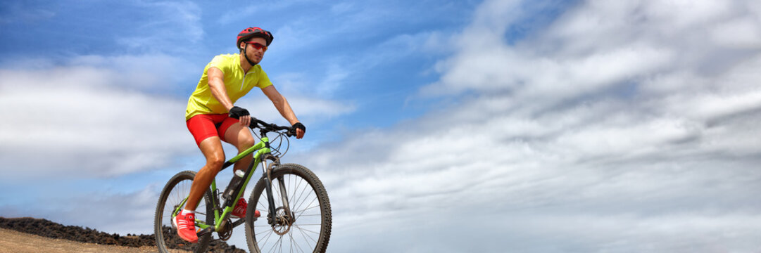 Sport athlete fitness training biking on mountain MTB bike landscape banner panorama. Copy space on blue sky background. Man cyclist riding bicycle outdoors. © Maridav