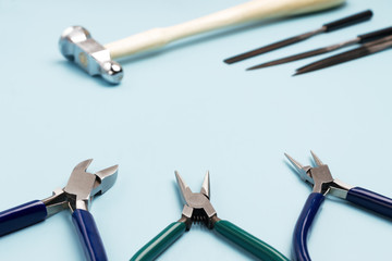 Jewelry tools. Pliers, hammer and files on a blue background