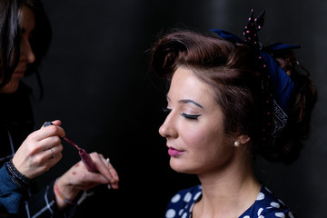 Obraz premium Makeup artist applies lips a red lipstick. Beautiful woman face. Perfect makeup on retro pinup or vintage pin up style