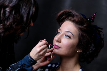 Makeup artist applies lips a red lipstick. Beautiful woman face. Perfect makeup on retro pinup or vintage pin up style