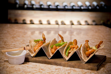Gourmet fish tacos featuring golden crispy battered fish strips on delicate flour tortillas, paired...