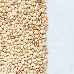Uncooked dry green lentils on concrete background, top view, square