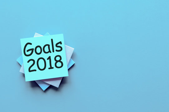 Goals 2018 text on blue note lying at blue background with empty space, template. New Year's promises for the next year, Mock up