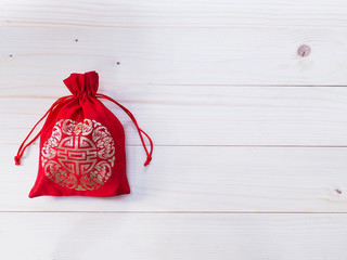 Red silky money bag with string on wood background