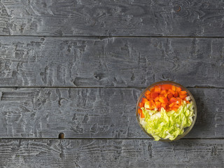 Cabbage and bell pepper in a glass bowl on a dark rustic table. Vegetarian food.