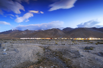 Scenic view of tents lining up in a landscape and beautiful mountain terrain at the background.