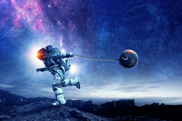 Naklejka premium Fantasy image with spaceman catch planet. Mixed media