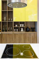 Modern kitchen furniture with contemporary kitchenware like hood, black induction stove and oven in house.