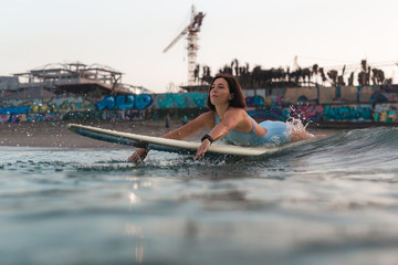 Young woman in bright bikini surfing on a board in ocean