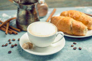 Cup of coffee with croissants on the rustic wooden background. Selective focus. Shallow depth of field.