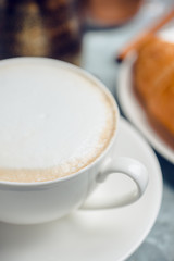 Cup of coffee with croissants on the rustic wooden background. Selective focus. Shallow depth of field.