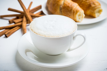 Cup of coffee with croissants on the rustic wooden background. Selective focus. Shallow depth of field.