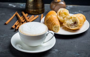 Cup of coffee with croissants on the rustic wooden background. Selective focus. Shallow depth of field.