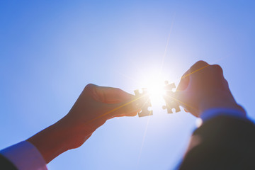 Hands connecting jigsaw puzzle at sunset effect, business success,teamwork,helping concept.