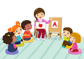 Group of preschool kids and teacher sitting on the floor.Teacher explaining alphabet to children