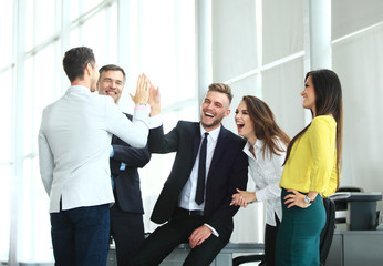 Happy successful multiracial business team giving a high fives gesture as they laugh and cheer their success