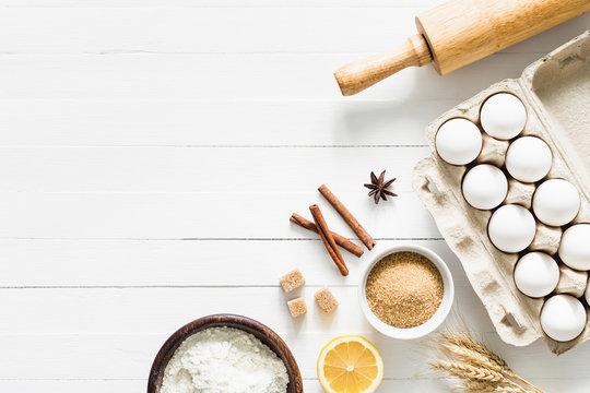 Baking ingredients on white table. White eggs, rolling pin, flour, sugar and spices. Home baking concept, baking cake or cookies ingredients