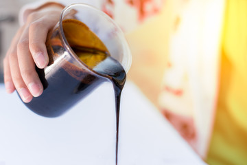 Molasses sugarcane on beaker. Droping molasses with hands. Molasses is the final product from the...