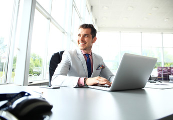 Fototapeta premium Portrait of young man sitting at his desk in the office