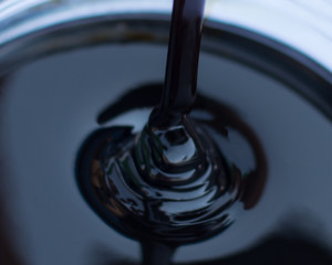 Molasses sugarcane on beaker blurred style background. Droping molasses with hands. Molasses is the...
