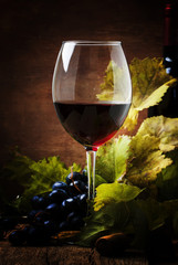 Red wine from grapes of cabernet sauvignon variety, still life in rustic style with berries and vine, vintage wooden background, selective focus © 5ph