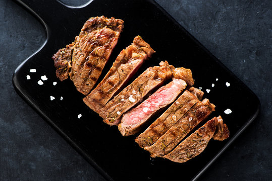 Slices Steak Ribeye with salt on a black cutting board